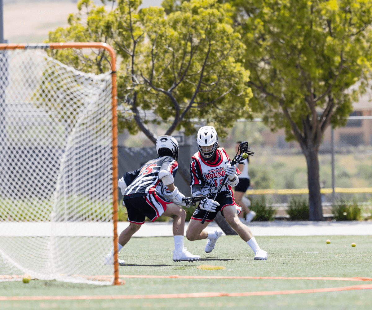 Two boys in full uniform in action during lacrosse practice